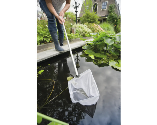 Vrouw gebruikt een schepnet in een tuinvijver