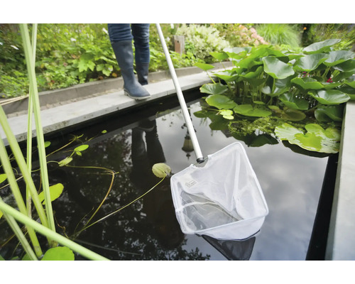 Persoon met schepnet voor het schoonmaken van een tuinvijver