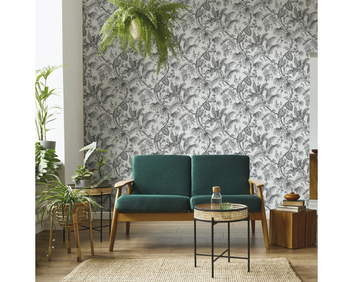 Woonkamer met bank, bijzettafels, kamerplanten, vloerkleed en behang met motief