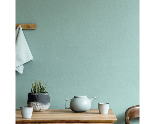 Scene met tafel, theepot, kopjes, plant en handdoek voor een gestructureerde wand