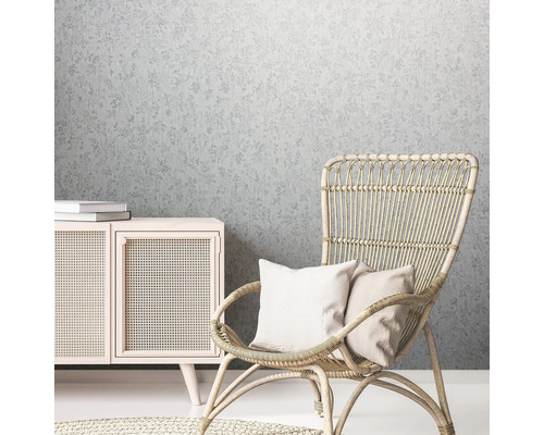Decoratieve woonsfeer met bloemenbehang, rotan stoel en houten commode