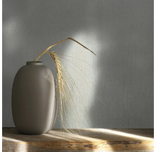 Decoratief behang met textielpatroon en vaas met graan op een houten tafel.