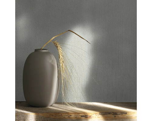 Decoratief behang met textielpatroon en vaas met graan op een houten tafel.