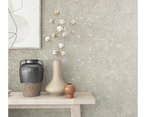 Close-up van een gedecoreerde tafel met vazen, katoentakken en een kunstwerk aan een gestructureerde muur