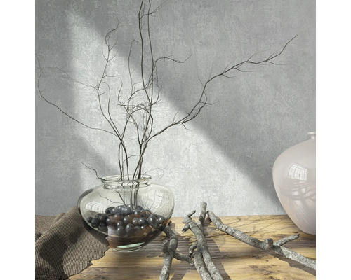 Decoratieve scène met een glazen vaas, takken en decoratieve ballen op een houten tafel.