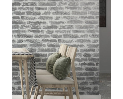 Interieur met een muurbehang in steenlook, stoelen en tafel.