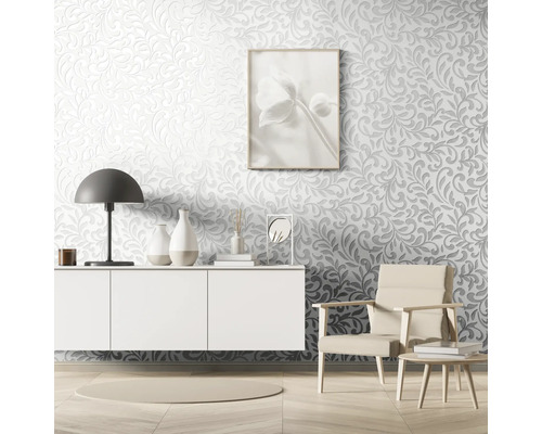 Woonkamer met reliëfbehang, dressoir, lamp, fauteuil en decoratieve artikelen.