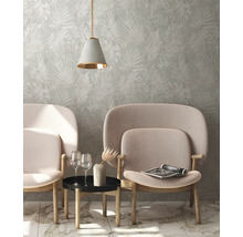 Woonkamer met behang met bladmotief, twee fauteuils, bijzettafel en hanglamp
