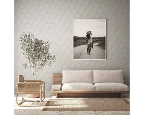 Woonkamer met bank, fauteuil, kamerplant, vloerkleed en ingelijste foto aan de muur