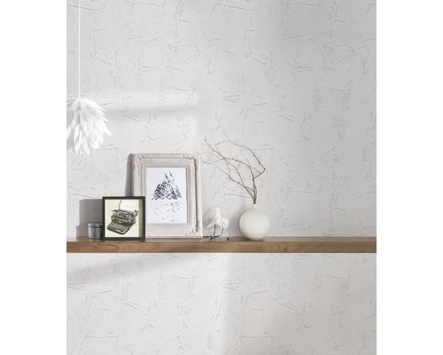 Lichte kamer met witte structuurbehang, versierd met planken, foto''s en een lamp.