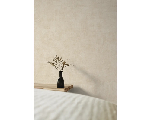 Decoratieve vaas met plantentak op een houten tafel voor een gestructureerde muur.