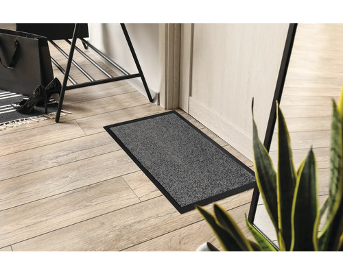 Grijze deurmat met zwarte rand in de entree.