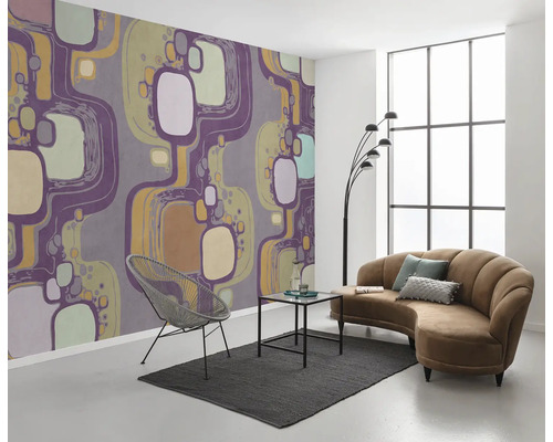 Woonkamer met patroonbehang, bank, fauteuil en vloerkleed