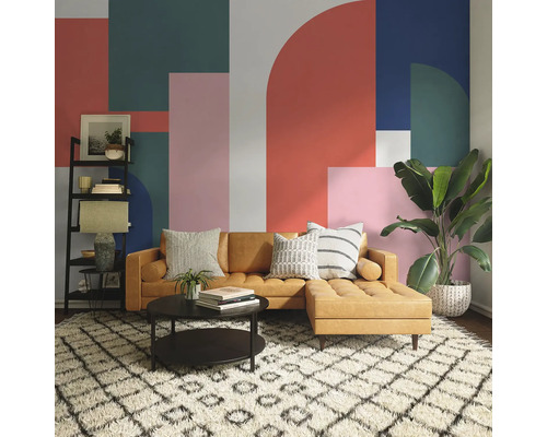 Woonkamer met bruine bank, salontafel, rek en kamerplant voor een muur met geometrisch patroon