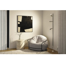 Woonkamerscène met fauteuil, staande lamp en kunstwerk aan de muur