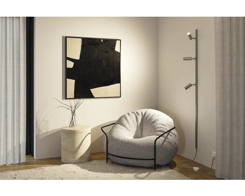 Woonkamerscène met fauteuil, staande lamp en kunstwerk aan de muur