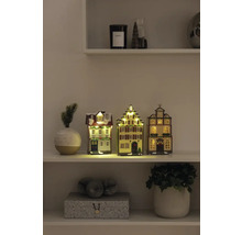Decoratieve kersthuisjes met verlichting op een plank