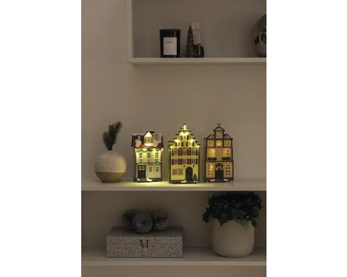 Decoratieve kersthuisjes met verlichting op een plank