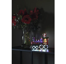 Decoratieve kersttrein met verlichting naast een boeket bloemen