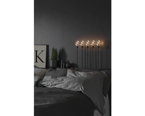 Decoratieve slaapkamer met bed, nachtlamp met vijf gloeilampen, potplant en foto