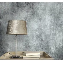 Close-up van een wandbehang met abstract patroon naast een lamp en boeken.