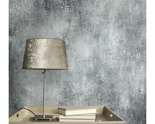 Close-up van een wandbehang met abstract patroon naast een lamp en boeken.