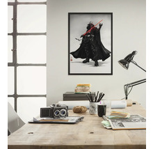 Ingelijste poster van Darth Vader met lichtzwaard aan de muur boven een bureau