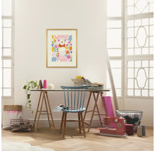 Een lichte ruimte met een bureau, een blauwe stoel, een naaimachine en een Winnie de Poeh poster aan de muur