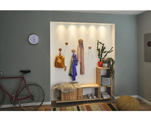 Entree met kapstok, bank, plank en decoraties in een heldere en uitnodigende stijl.