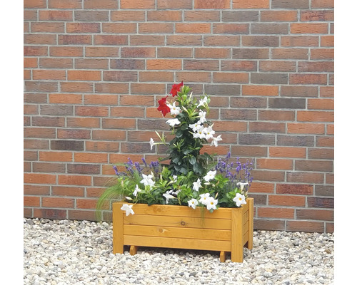 Houten bloembak met rode en witte beplanting voor een bakstenen muur