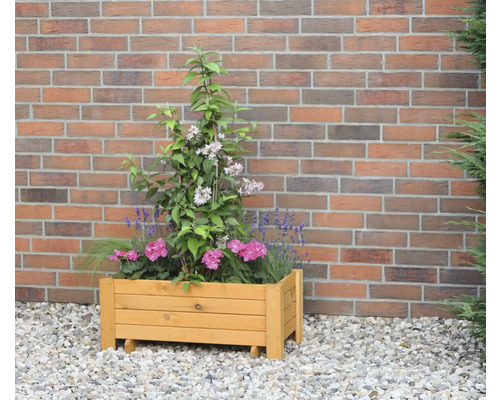 Houten plantenbak met bloemen voor een bakstenen muur