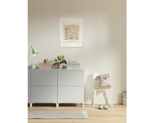 Woonkamer met dressoir, lamp, kamerplant, fotolijst en stoel met rugzak