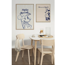 Eetkamer met twee ingelijste posters van Mickey Mouse en Minnie Mouse aan de muur boven een tafel met stoelen