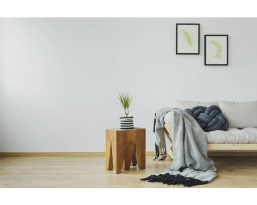 Lichte kamer met houten bijzettafel, plant, bank, deken en kussen