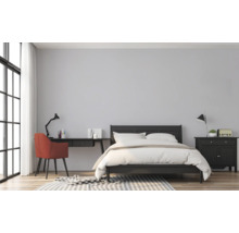 Slaapkamer met bed, bureau en stoel in een lichte kamer