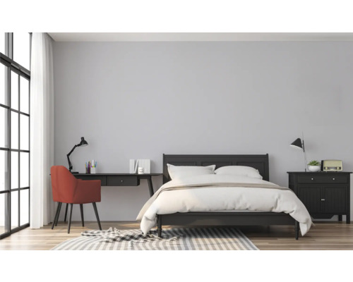 Slaapkamer met bed, bureau en stoel in een lichte kamer