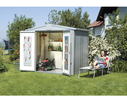 Tuinscene met tuinhuis, grasmaaier en ontspannende vrouw op een ligstoel