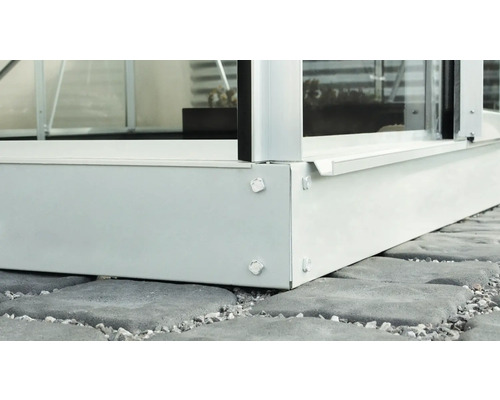 Detailopname van een kas met funderingsframe op stenen bestrating