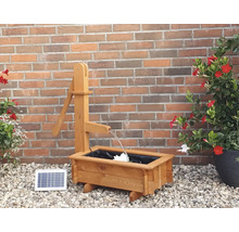 Houten fontein met zonnepaneel voor een bakstenen muur