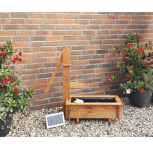 Tuinscene met houten fontein met zonnepomp en plantenbakken voor een bakstenen muur