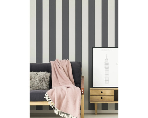 Scene met gestreept behang, bank met deken, kussen en een ingelijste Londense prent op een nachtkastje.