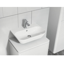 Moderne badkamer wastafel met kraan op een wastafelmeubel met ribbelstructuur.