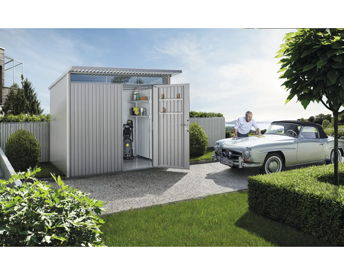 Metalen tuinhuis met open deuren en man die auto poetst