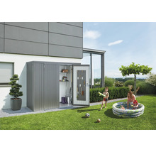 Metalen tuinhuis met open deur, gereedschap en planken in een tuin met spelende kinderen