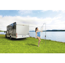 Vrouw onder campingdouche naast camper op gazon aan meer