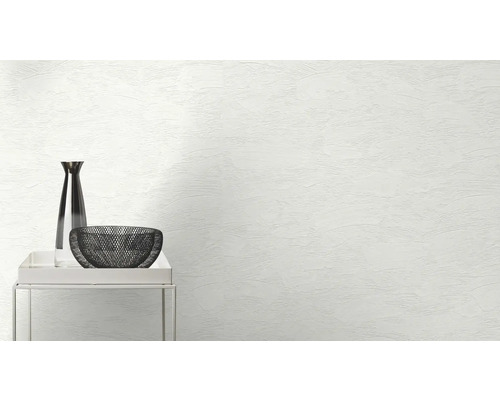 Decoratieve vaas en schaal op een klein tafeltje voor een muur met stucwerk textuur.