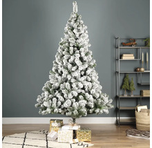 Versierde, besneeuwde kerstboom met geschenken in de woonkamer.