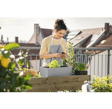 Vrouw op een balkon met een verhoogde tuinbak en planten