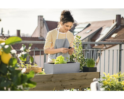 Vrouw op een balkon met een verhoogde tuinbak en planten