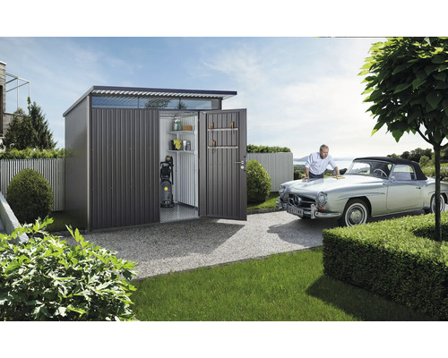 Metalen tuinhuis met open deuren, planken, hogedrukreiniger en een man die een auto poetst